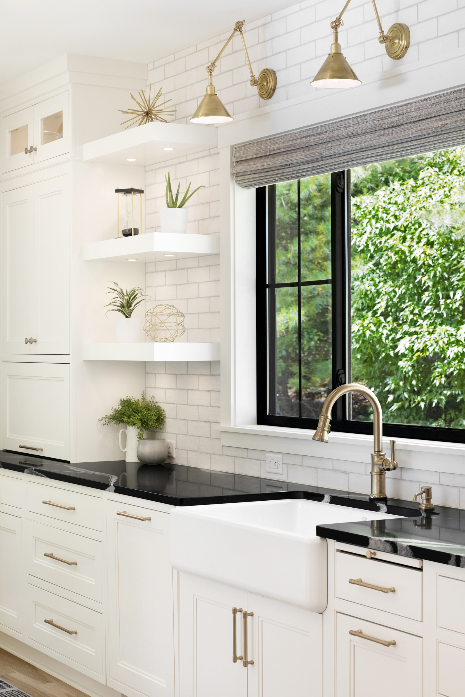 Kitchen remodel with white cabinets, black countertops, and gold fixtures