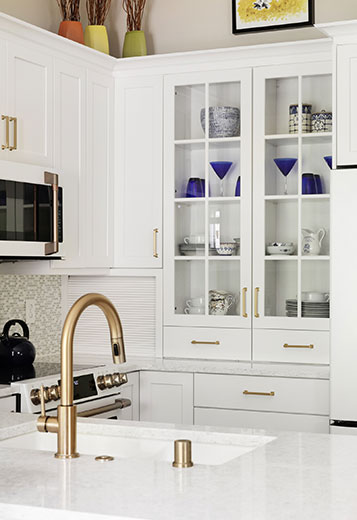 Compact kitchen remodel with white cabinets with glass panel doors